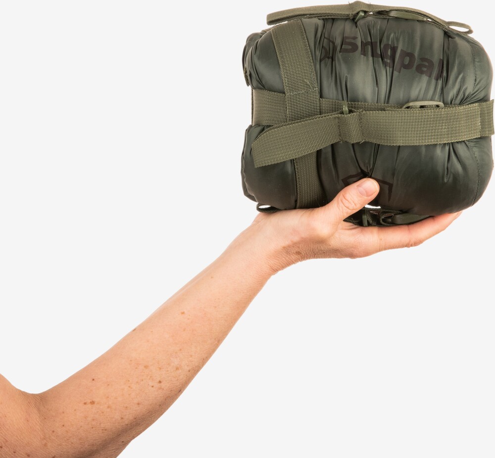 Sammenpakket olivengrøn Snugpak Softie Elite 1 sovepose i kompressionspose holdt i én hånd