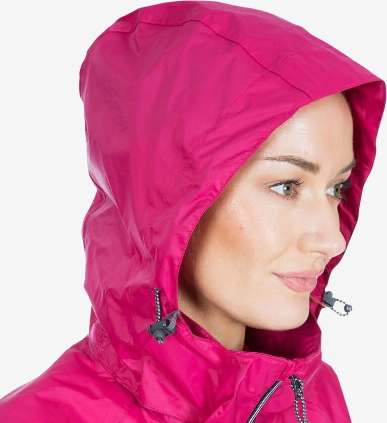 Kvinde set fra siden med hætten på en pink regnjakke slået op og strammet om ansigtet