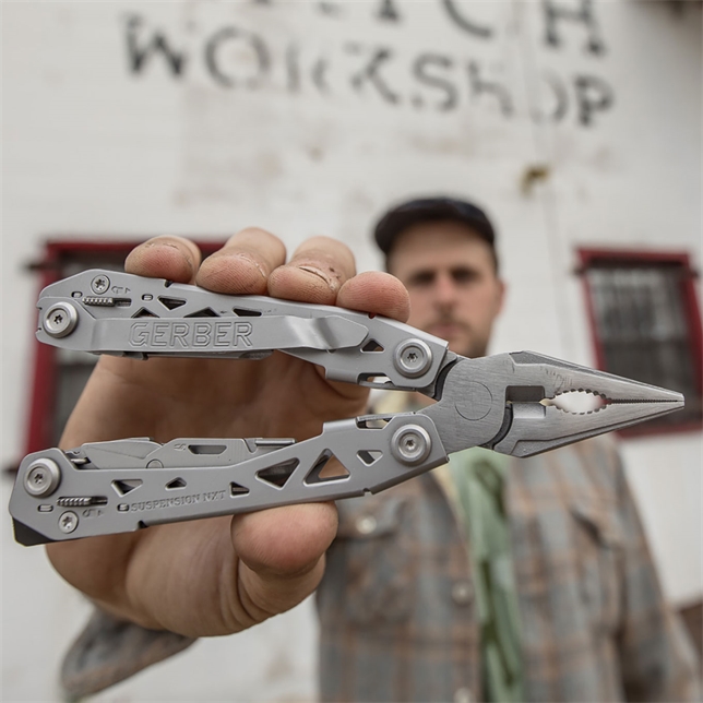 Mand i ternet skjorte holder et udfoldet multitool med tangen frem mod kameraet