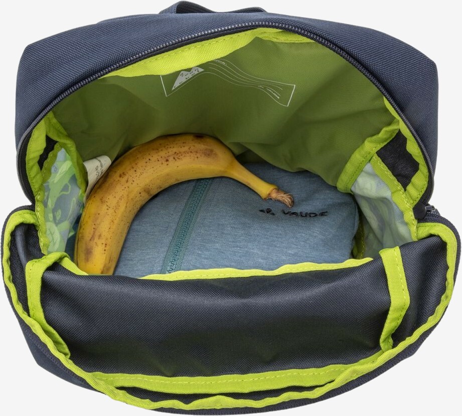 Åben børnerygsæk set oppefra, pakket med en banan og en sammenfoldet trøje