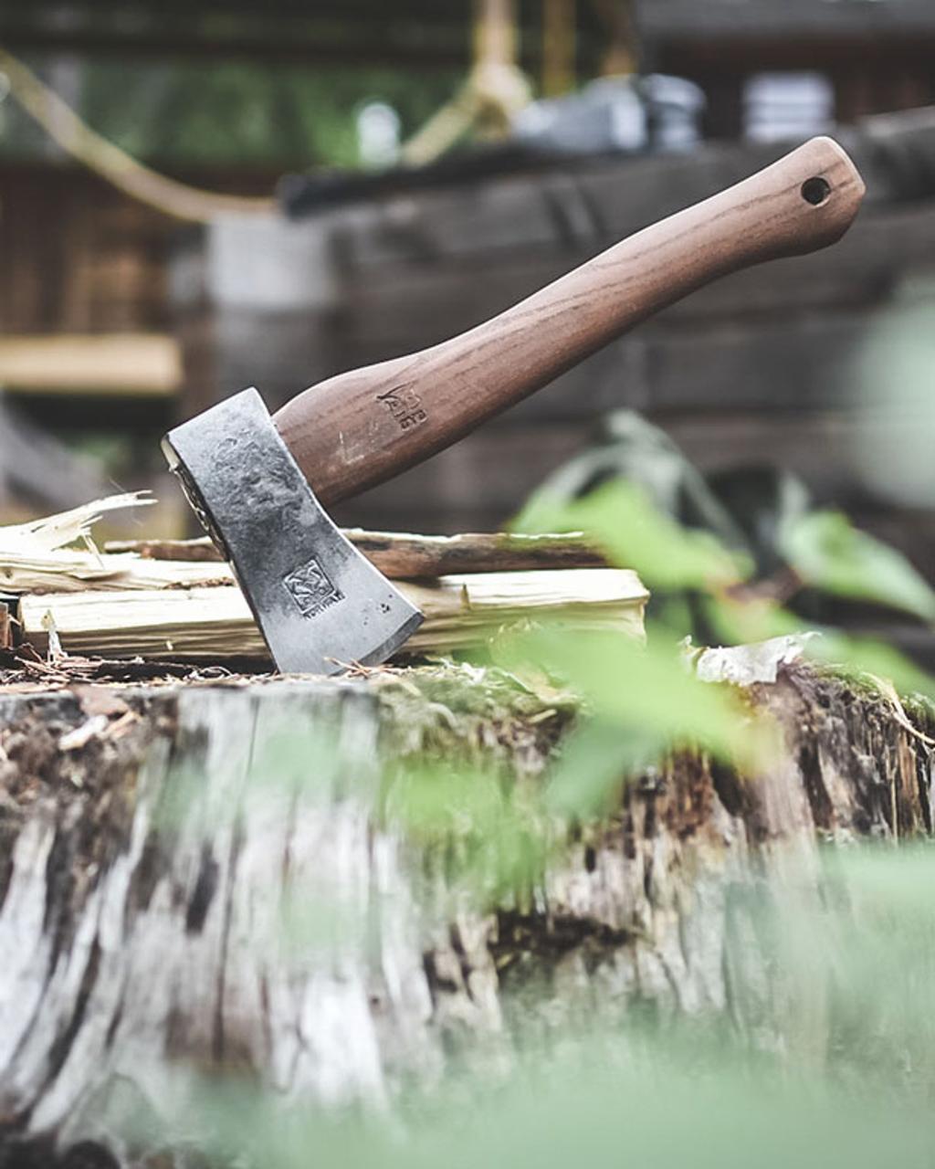 Lille økse med træskaft hugget fast i en huggeblok med kløvet optændingstræ ved siden af