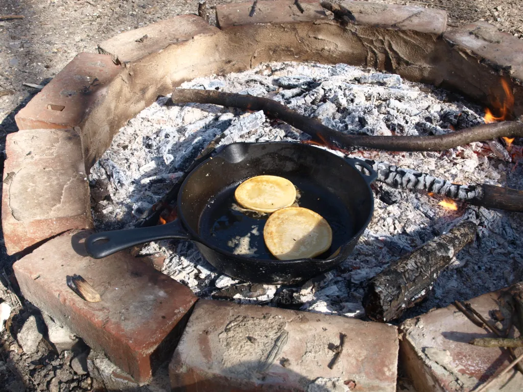 To amerikanske pandekager tilberedes på en bålpande, der stå i gløderne